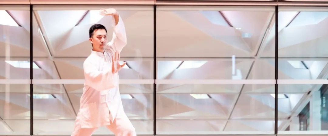 man in white tshirt makes tai chi movements with hands