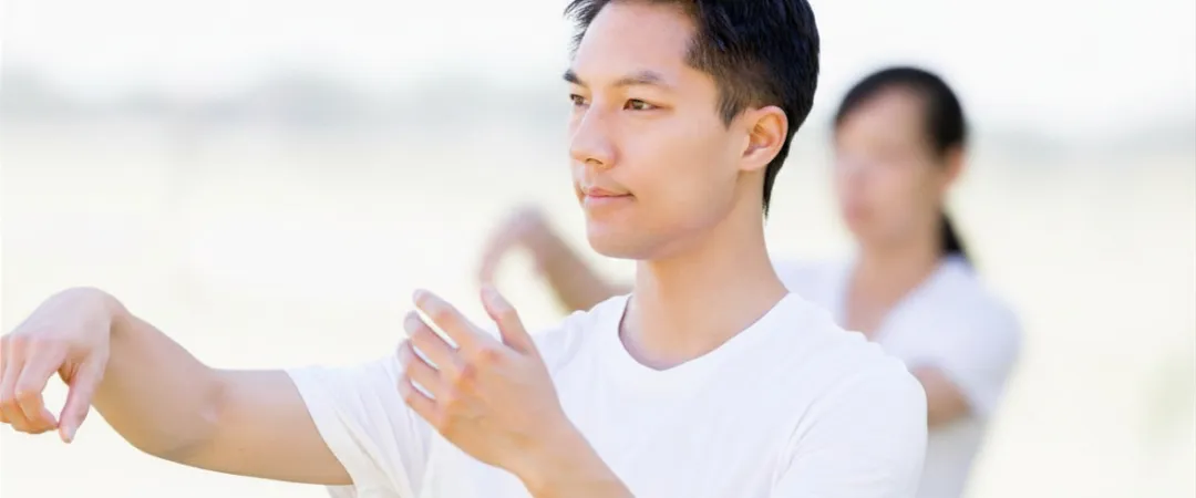 man in white tshirt makes tai chi movements with hands