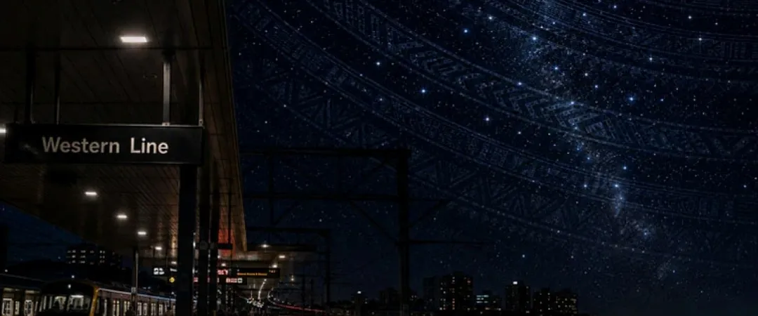 Nighttime Western Line train platform beside city lights and water, with a star-filled galaxy arching overhead, creating a dreamy atmosphere.