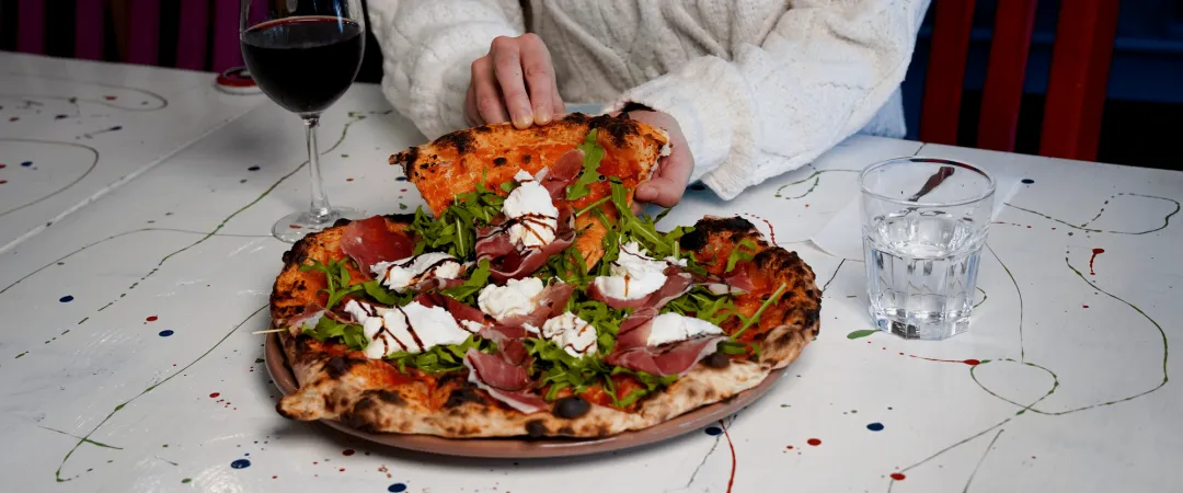 person grabbing a slice of pizza