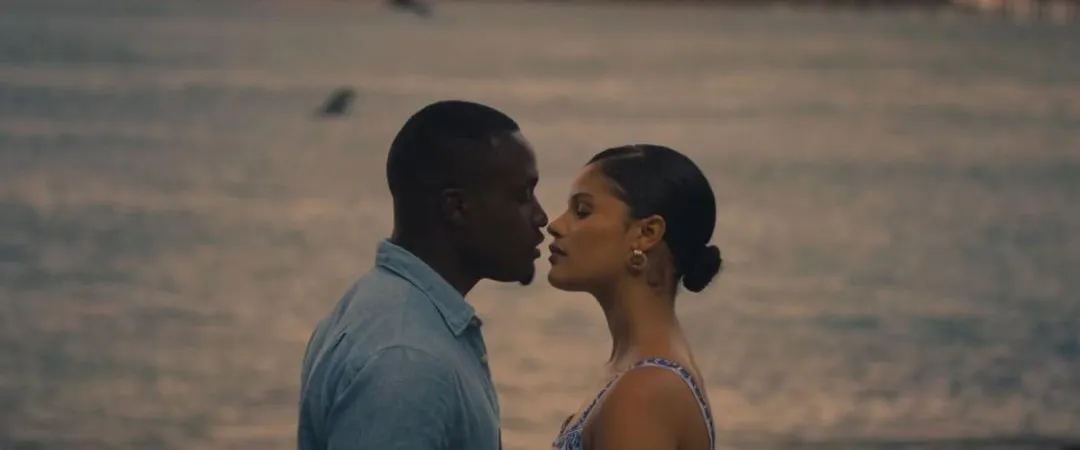 Man and woman kissing over the water against a sunset