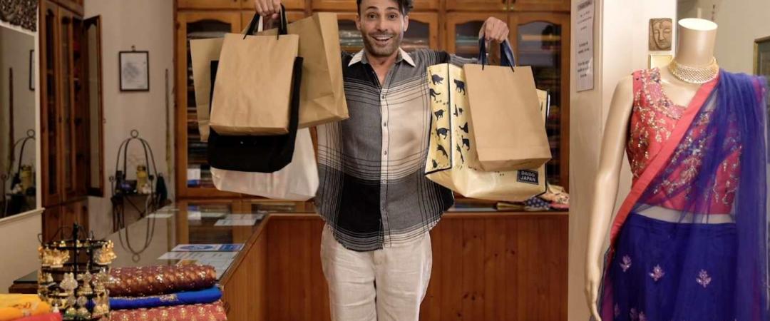 man inside saree shop holding up shopping bags