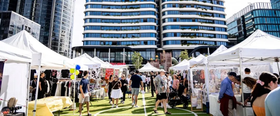 Markets with white tents, set on backdrop of apartment buildings