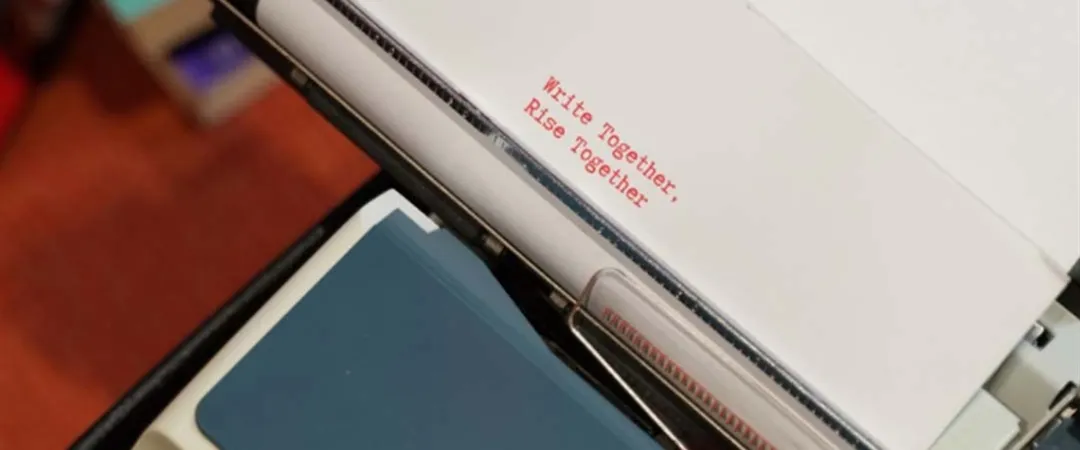 Close-up of a vintage typewriter with paper reading “Write together, rise together,” conveying creativity, collaboration, and encouragement.