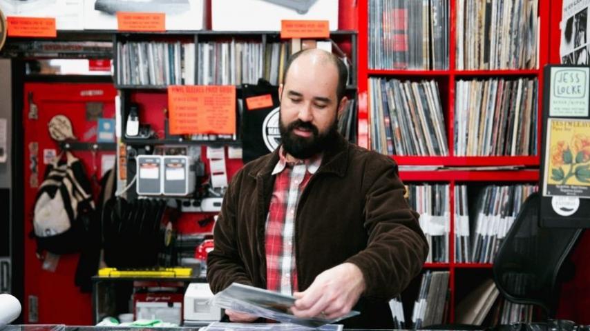 record store owner taking a record out of vinyl sleeve 