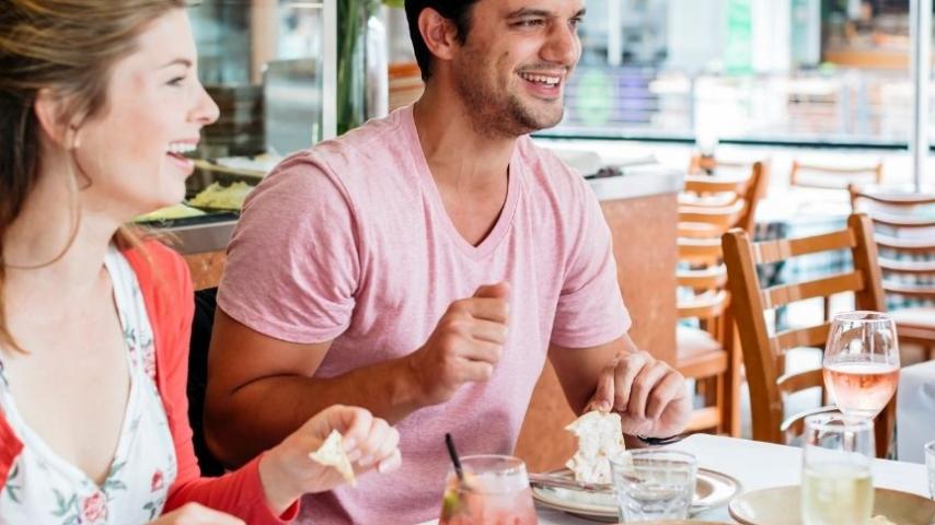 man and woman laughing as they enjoy a meal