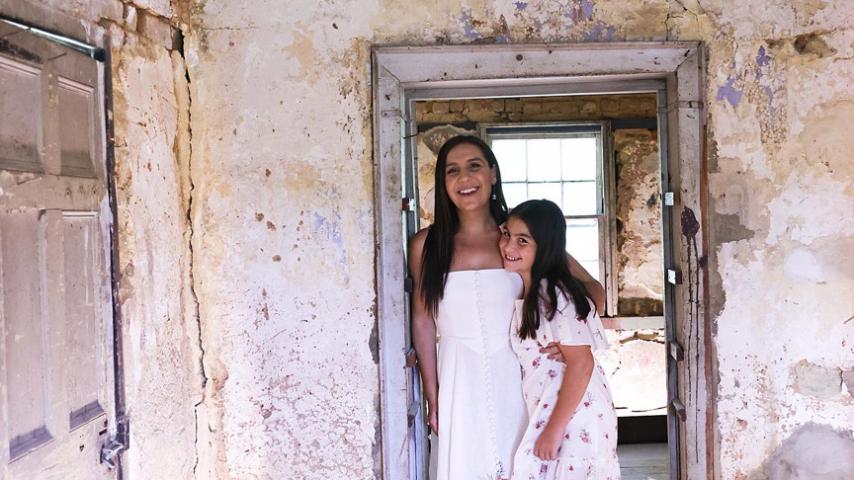mother and daughter standing in doorframe of old property