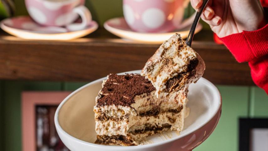 Pulling piece tiramisu away from a white cake  