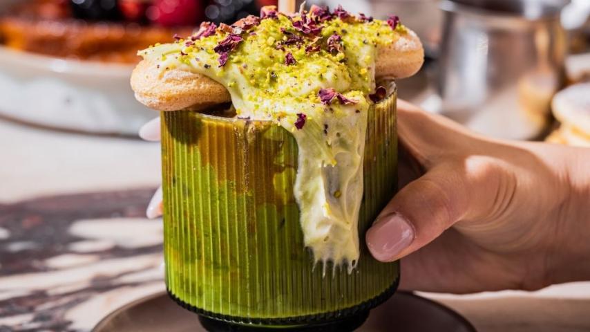 Glass full of green liquid with cream overflowing from cup