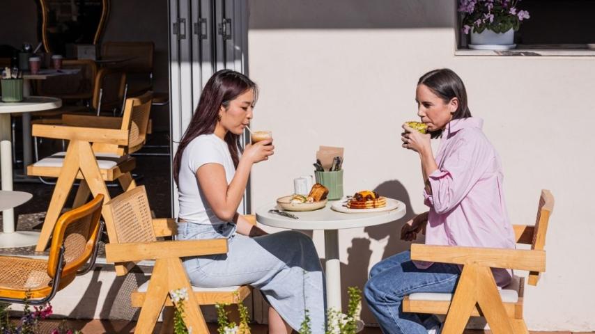 Two women sipping coffee sitting down on women chair out the front of Sabah