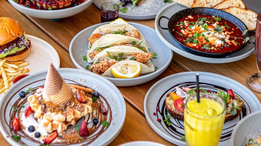 Tabe full of yummy plates of food like fish tacos, coconut french toast, eggs