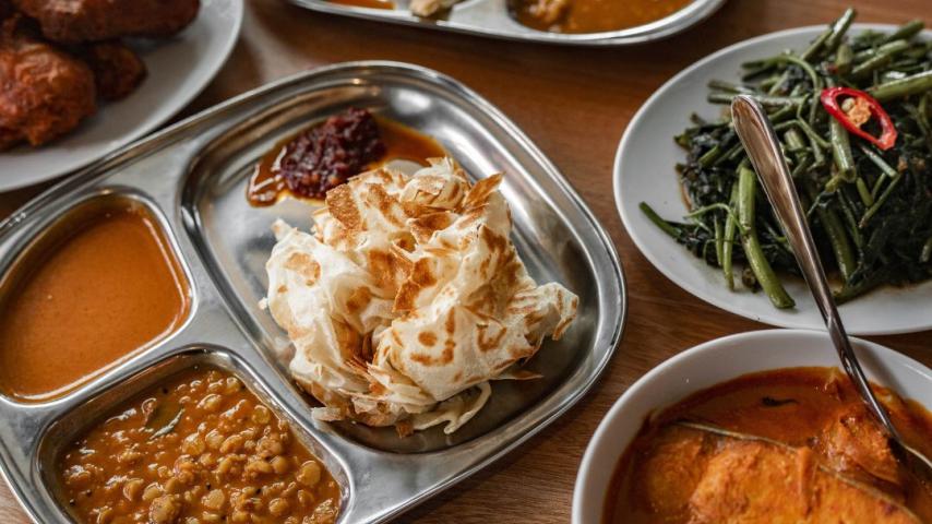 Silver platter of roti, red sauce, greens, rice and meats