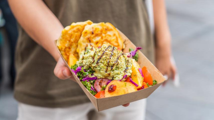 Hand holding a cardboard box with gozleme with lemon and tomato