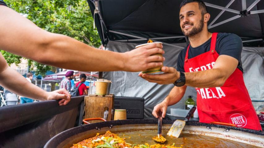 Man in red apron handing over bowl of fresh seafood Palella 